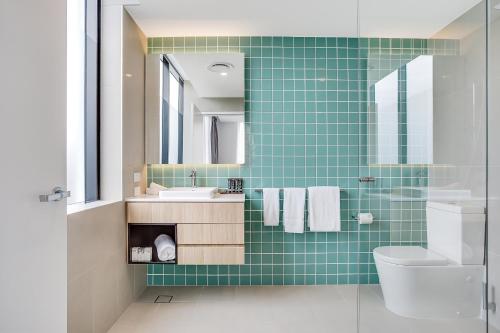 黄金海岸鲨鱼的咒语酒店的绿色瓷砖浴室设有水槽和卫生间