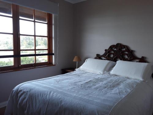 比亚里卡Condominio La Puntilla Km 2 Camino Villarrica Pucon的一间卧室配有一张带白色床单的床和两个窗户。