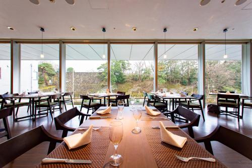 金泽KKR金泽大酒店的餐厅设有桌椅和大窗户。