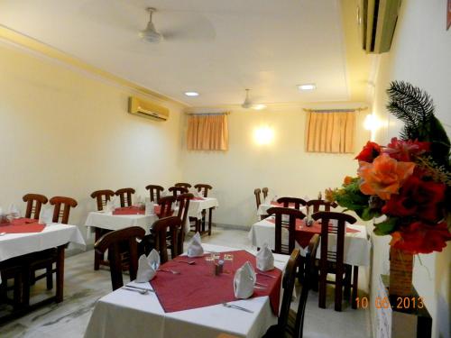 新德里月光集市塔拉宫酒店的用餐室配有白色的桌椅和鲜花