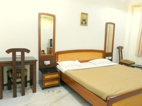 新德里月光集市塔拉宫酒店的一间卧室配有一张床、一张桌子和一面镜子
