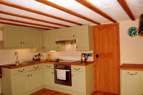 KnivetonHillocks Cottage, Kniveton的厨房配有白色橱柜和木制天花板