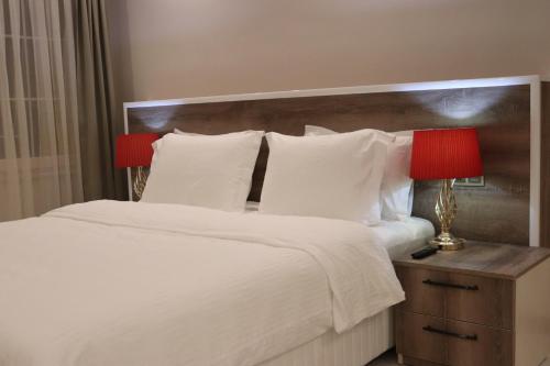 ÇekirgeYankı Hotel的一张带白色枕头的床和床头柜上的红灯