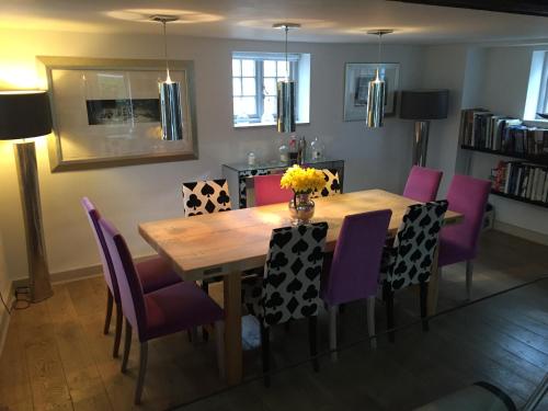 多尔金Castle Mill Bed and Breakfast的一间带木桌和紫色椅子的用餐室