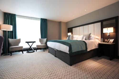 贝尔法斯特Grand Central Hotel Belfast的酒店客房,配有一张床和两把椅子
