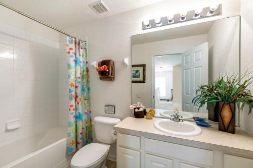 奥兰多Olivia's Dream Villa on WindsorHills的一间带水槽、卫生间和镜子的浴室