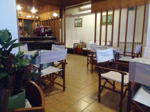 莫内利亚意大利酒店的一间设有白色椅子和桌子的用餐室