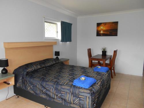 Thursday IslandTI Motel Torres Strait的卧室配有1张床、1张桌子和1把椅子