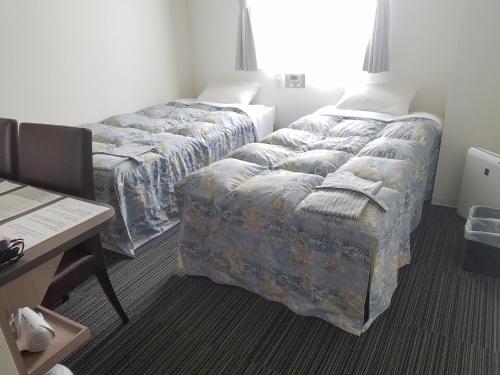 MurayamaMurayama Nishiguchi Hotel的酒店客房配有两张床和一张书桌