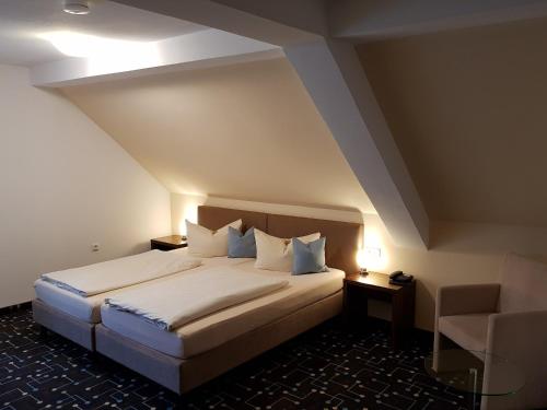 Pliening库尼格酒店的一间卧室配有一张大床和一把椅子