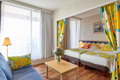 比亚里茨Résidence Vacances Bleues Le Grand Large的酒店客房,设有两张床和一张沙发