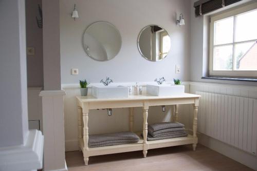 博尔赫隆'Hof der Heerlijckheid'的浴室设有两个水槽和两面墙上的镜子