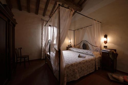乌尔巴尼亚Agriturismo Valpietro的一间卧室配有一张天蓬床和一把椅子