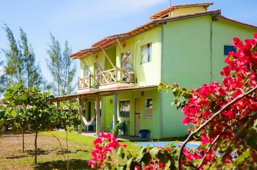 埃斯坦西亚Pousada Villa Verde的带阳台和粉红色鲜花的绿色房屋