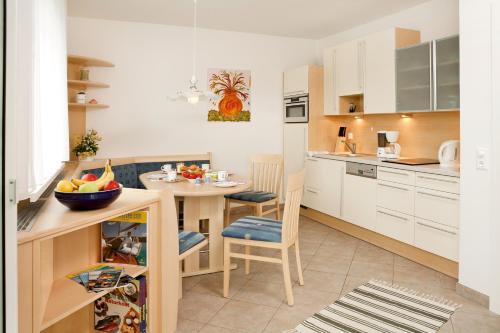 沃尔特湖畔韦尔登哈斯柯坦公寓的厨房配有白色橱柜和一张带一碗水果的桌子