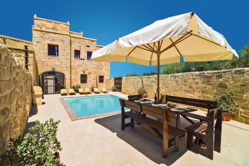 ŻejtunVilla Valletta的游泳池旁带遮阳伞的桌子