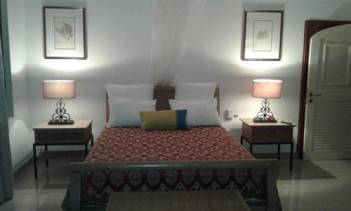 Post of FlacqShanti Nivas的一间卧室配有一张床,两台桌子上放着两盏灯