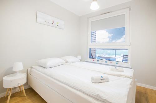 格丁尼亚Apartments Gdynia Na Fali with Parking by Renters的卧室配有白色的床和窗户。