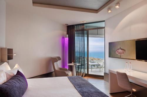 特拉维夫Royal Beach Hotel Tel Aviv by Isrotel Exclusive的酒店客房设有一张床和一张书桌,享有美景。