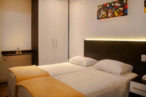 圣保罗布瑞斯皇宫酒店的一间卧室设有两张床,墙上挂着一幅画