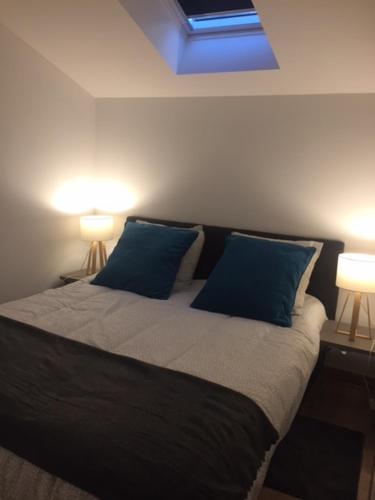克卢尼Gîte des Charmilles /La Maison des Gardes的一间卧室配有一张带蓝色枕头的床和两盏灯。