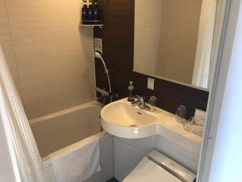 藤泽湘南藤泽阿尔蒙特宾馆的一间带水槽和浴缸的小浴室