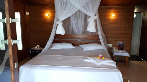 沙璜贝利佩里斯民宿的一间卧室配有一张带天蓬的白色床