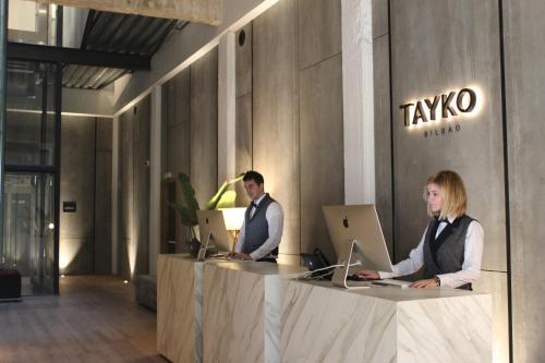 毕尔巴鄂Hotel Tayko Bilbao的两个人坐在柜台上,手提电脑