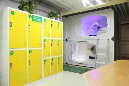 武汉武汉无忧太空舱酒店的一间设有黄色储物柜和洗衣机的客房