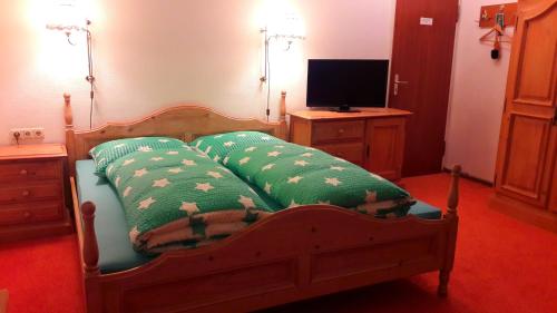 布劳恩拉格Hotel garni Am Hochwald的一间卧室配有一张带两个枕头的床和电视。