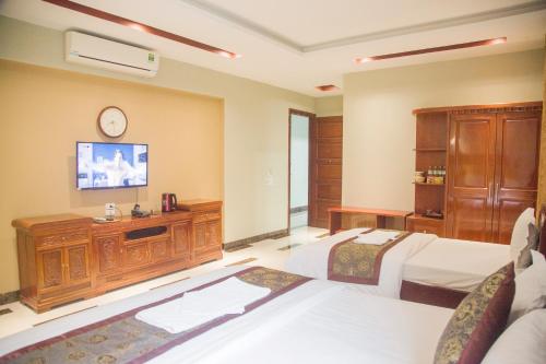 老街市Khách Sạn Hoàng Gia Lào Cai - Hoang Gia Hotel的一间卧室设有两张床,墙上配有电视。
