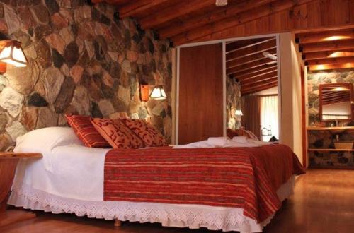 贝尔格拉诺将军镇Posada del Halcón - Cabañas y Suites的一间卧室配有一张石墙床