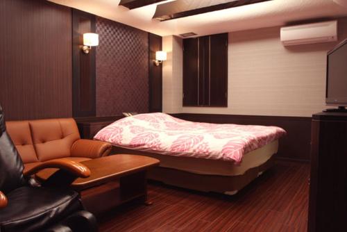 厚木Hotel GOLF Atsugi (Adult Only)的一间卧室配有一张床、一把椅子和一张沙发