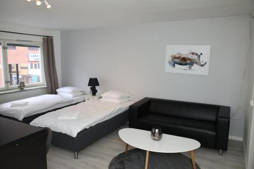 韦斯特罗斯Fastliving Apartment Hotel的客房设有两张床、一张沙发和一张桌子。