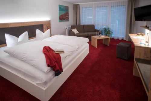 塞尔巴赫加尔尼施米尔德奥森酒店的卧室配有一张白色大床和红地毯