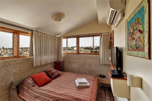 耶路撒冷Into Jerusalem heart的一间卧室设有一张床、一台电视和窗户。