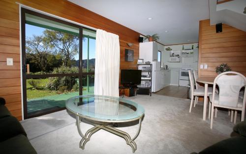 奥波蒂基Capeview Cottage的一间带玻璃桌的客厅和一间厨房