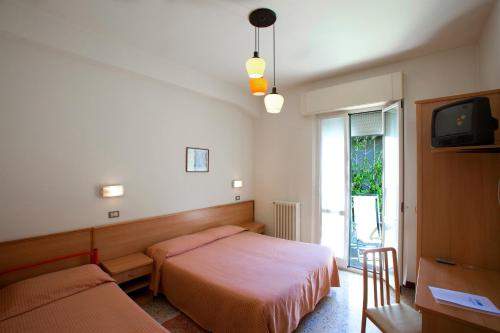 西尼加利亚Albergo Moretti的一间卧室设有两张床、一台电视和一扇窗户。