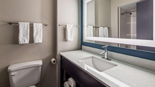 岩石丘速8石山酒店的一间带水槽、卫生间和镜子的浴室