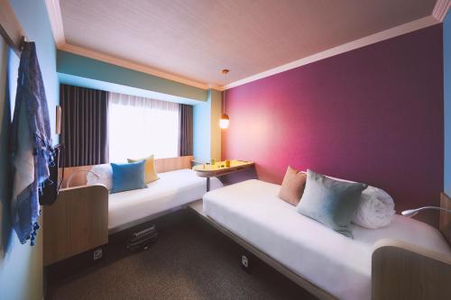 旭川OMO7 Asahikawa by Hoshino Resorts的一间设有两张床和紫色墙壁的客房