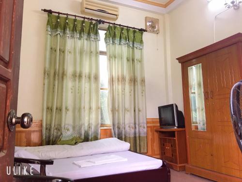 Yên BáiVân Anh Guesthouse的客房设有床和带窗帘的窗户。
