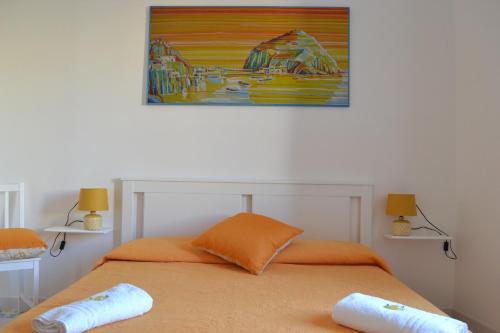 伊斯基亚L'Agrumeto的一张带两个枕头的床和墙上的绘画