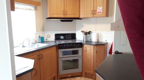 Winthorpe6 berth on Northshore En-suite Sunnyside的厨房配有木制橱柜和炉灶烤箱。