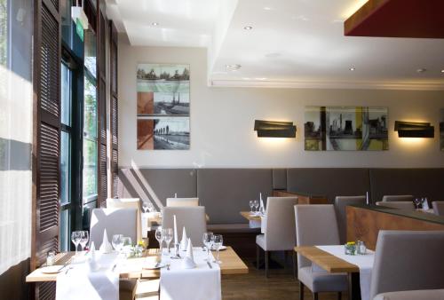 多特蒙德多特蒙德施泰根博阁酒店的配有木桌和白色椅子的餐厅