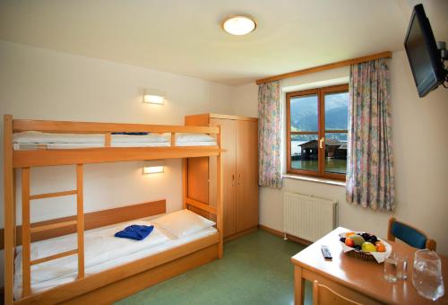 滨湖采尔滨湖采尔尤格斯酒店的客房设有两张双层床、一张桌子和一张书桌。
