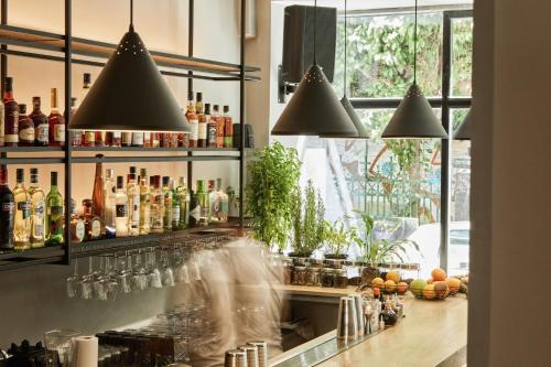 雅典雅典艺术家酒店的一个带吧台的酒吧,配有瓶子和眼镜