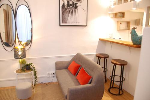 图卢兹Le typique - coeur de ville的客厅配有灰色沙发和橙色枕头。