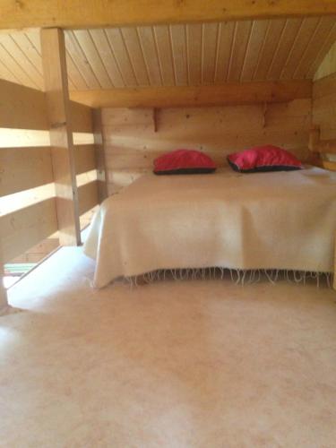 艾克塞恩维克斯Les Marmottes的木制房间的一个床位,上面有红色枕头