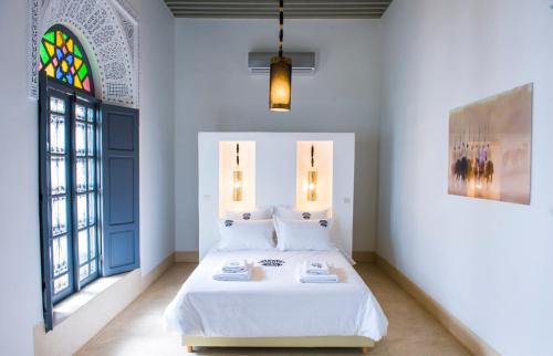梅克内斯里亚德亚姆查旅馆的一间卧室设有一张床和一个彩色玻璃窗