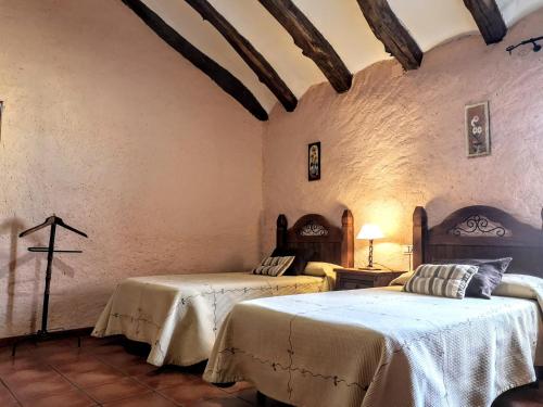 塞利亚Casa rural Las Masadas的卧室配有两张床,墙上有一个十字架